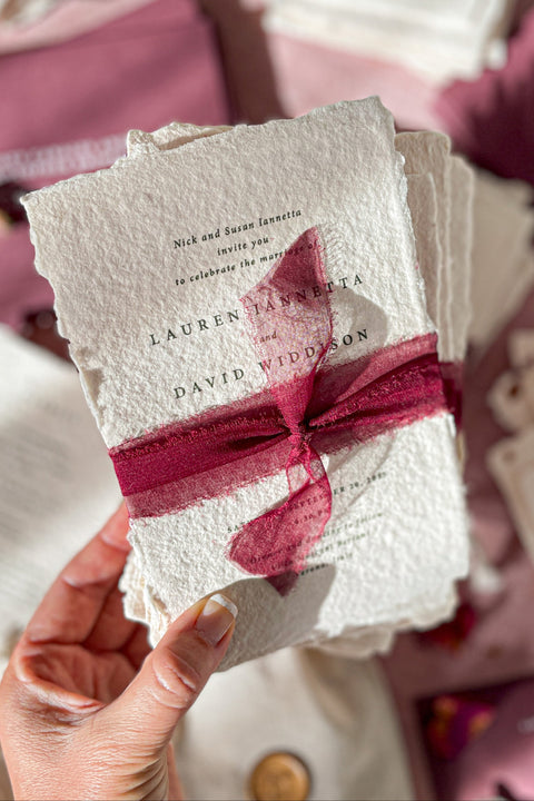 Romantic, rich, and full of timeless charm - this handmade paper wedding invitation suite is the perfect harmony of texture, elegance, and deep color. Each invitation is printed on luxurious cotton handmade paper with naturally deckled edges, exuding an organic and artisanal feel that makes every piece truly one of a kind. The suite is beautifully complemented by deep burgundy envelopes and tied with flowing silk chiffon ribbons in wine red, adding warmth, passion, and sophistication.