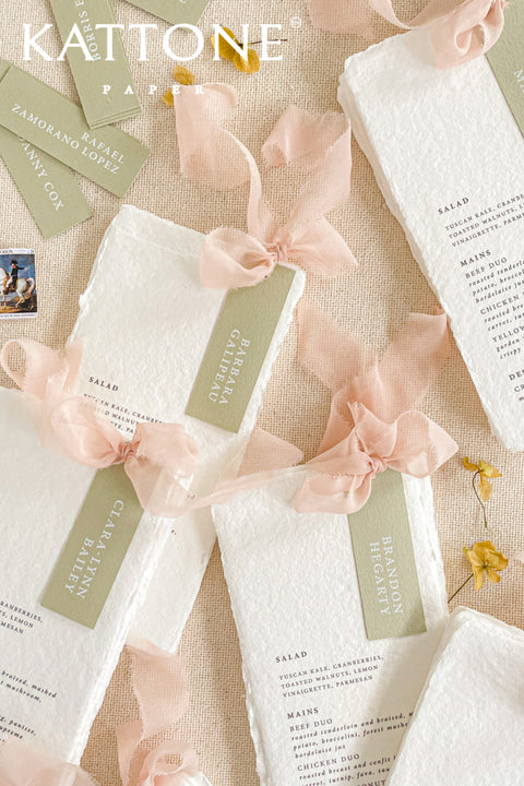 Elevate your tablescape with our handmade paper wedding menus with personalized name tags, crafted from soft cotton paper with naturally deckled edges. Each menu exudes fine-art elegance, featuring delicate typography, custom color tags, and flowing chiffon ribbons - blending romance, craftsmanship, and sophistication. Perfect for luxury, garden, and destination weddings, these menus double as keepsake place cards.