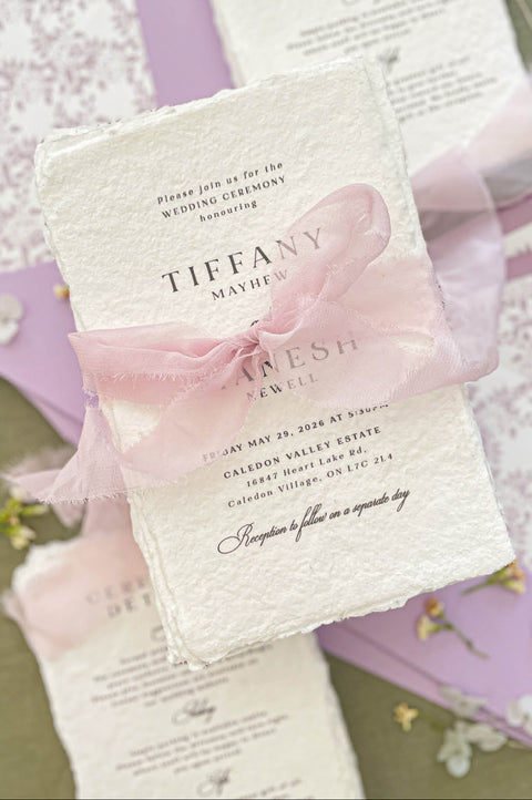 Close up of textured handmade cotton paper invitation showing organic deckled edges and elegant script typography.