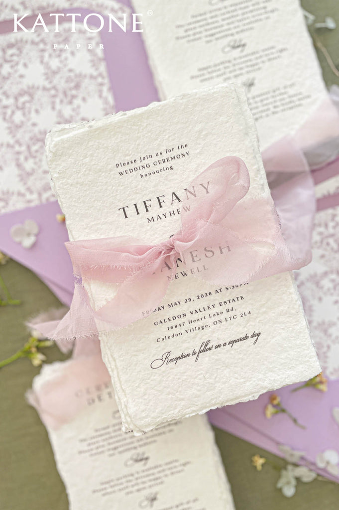 Close up of textured handmade cotton paper invitation showing organic deckled edges and elegant script typography.