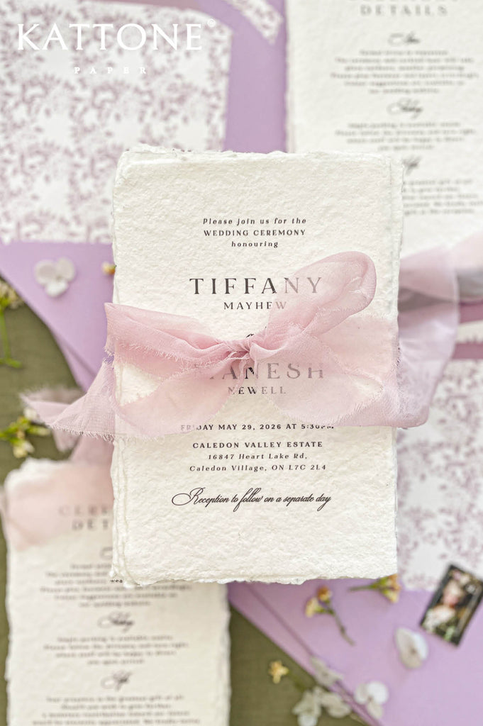 Hand-torn blush silk ribbon tied around handmade wedding invitation creating a soft romantic presentation.