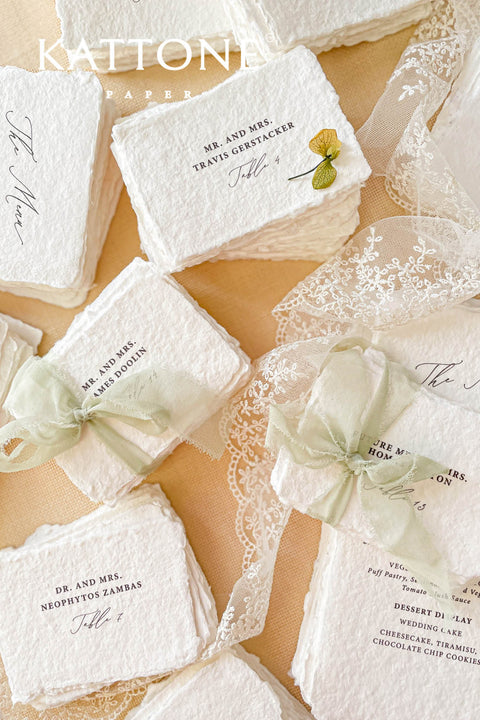 Add refined, old-world elegance to your event with our handmade paper place cards, crafted from luxurious cotton rag paper and finished with naturally torn deckled edges. Each card features elegant serif typography and optional soft green ribbon, creating a timeless fine-art aesthetic perfect for weddings, rehearsal dinners, and sophisticated celebrations. Their artisanal texture, organic silhouette, and customizable details bring beauty and authenticity to every tablescape.