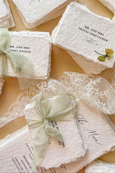 Add refined, old-world elegance to your event with our handmade paper place cards, crafted from luxurious cotton rag paper and finished with naturally torn deckled edges. Each card features elegant serif typography and optional soft green ribbon, creating a timeless fine-art aesthetic perfect for weddings, rehearsal dinners, and sophisticated celebrations. Their artisanal texture, organic silhouette, and customizable details bring beauty and authenticity to every tablescape.