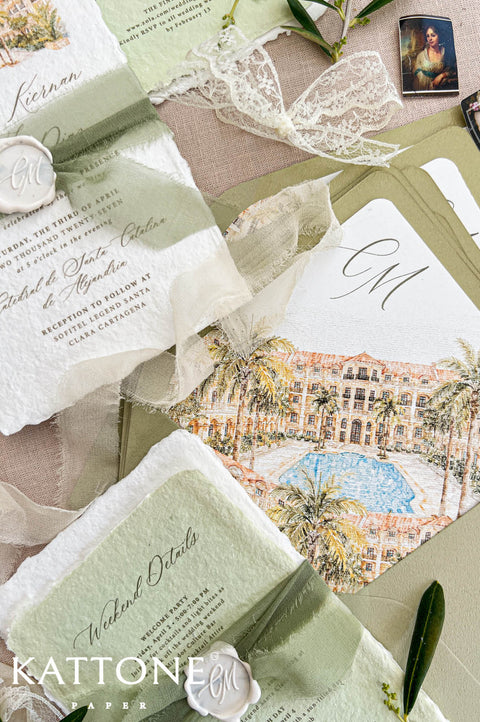 Close-up of an olive green wedding envelope with a custom watercolor liner illustrating a tropical resort, palm trees and blue swimming pool, alongside an ivory handmade wedding invitation and sage green weekend details card with silk ribbon.