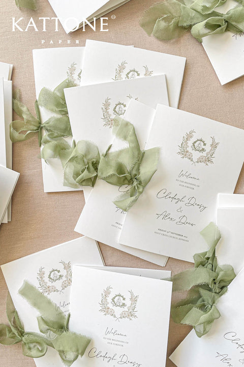Wedding ceremony program with custom watercolor monogram and soft botanical greenery.