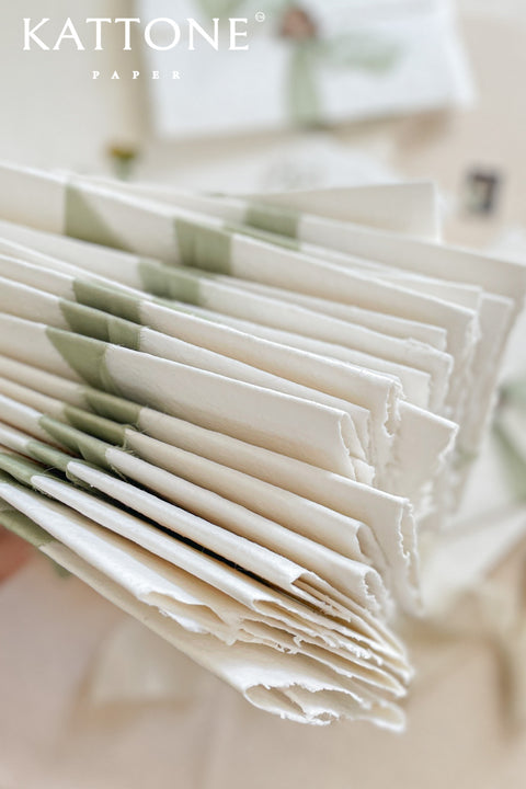 This exquisite trifold wedding invitation set offers a blend of modern design and personalized artistry. Each handmade paper invitation features a beautifully hand-painted custom watercolor monogram of your initials, creating a unique and personal touch. The convenient trifold design offers ample space for all your wedding details, all wrapped in a beautifully elegant package that your guests will adore.