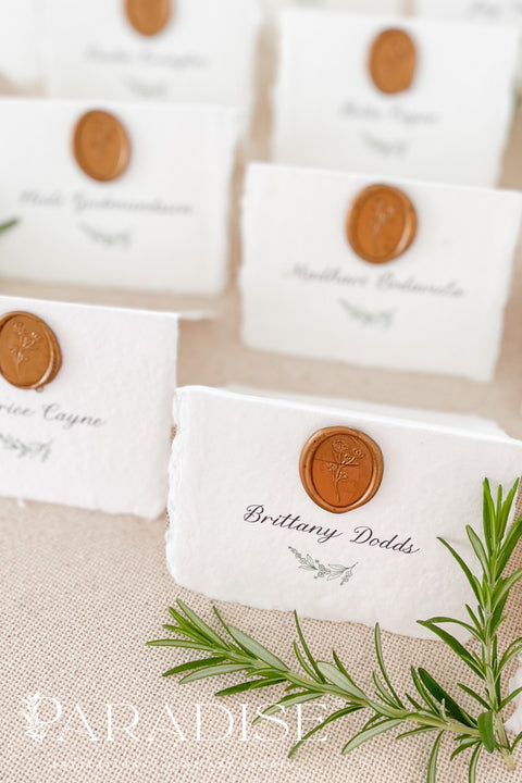 Elevate your wedding or event with our handmade paper place cards, crafted from luxurious cotton rag paper and finished with naturally torn deckled edges. Each card is adorned with a warm copper wax seal and elegant calligraphy, creating a timeless, fine-art detail that enhances any tablescape. Designed to bring organic texture, charm, and sophistication, these artisan place cards make your seating display unforgettable.