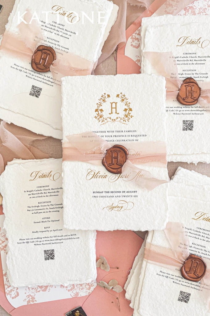 Blush silk ribbon wedding invitations finished with a custom wax seal monogram on handmade deckle edge paper.
