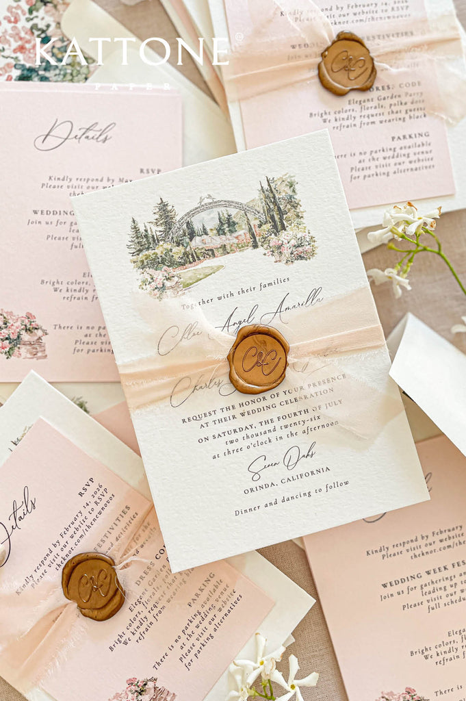 Flat lay of luxury wedding stationery including handmade paper invitations, details cards, RSVP cards, and custom venue artwork.