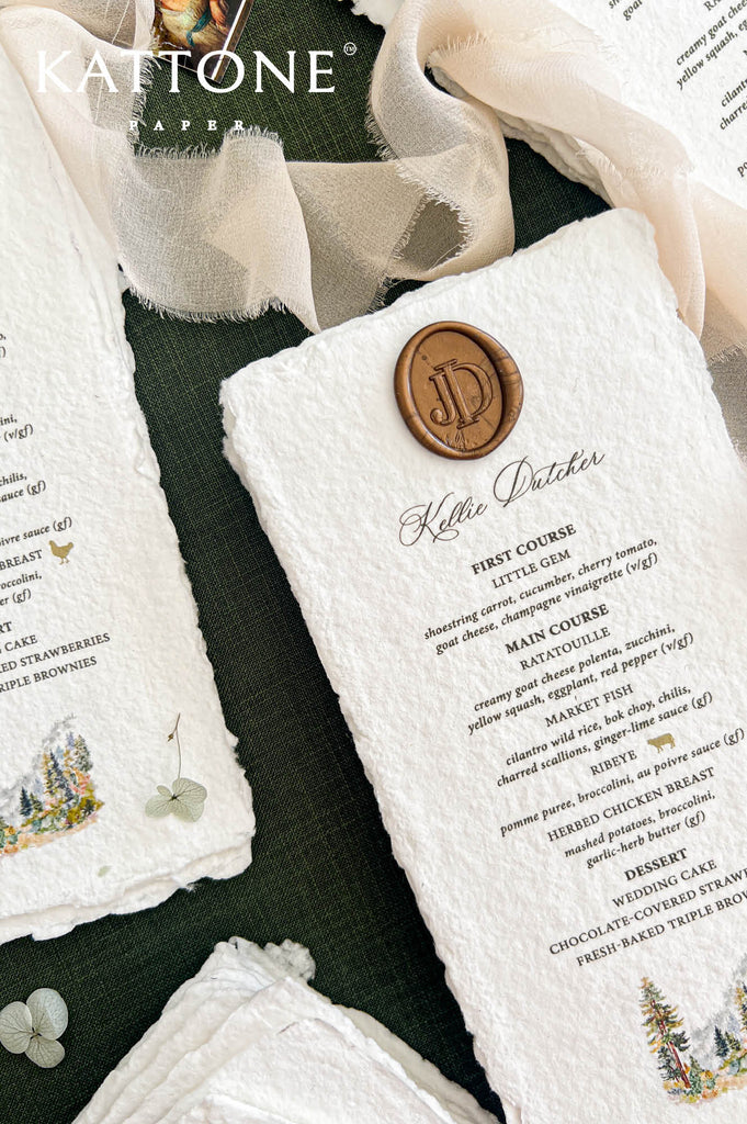 Detailed close-up of a luxury personalized wedding menu on textured ivory handmade paper, featuring naturally deckled edges, an antique gold monogram wax seal, an individual guest's name in elegant script, black dinner menu lettering, and a hand-painted woodland watercolor illustration.