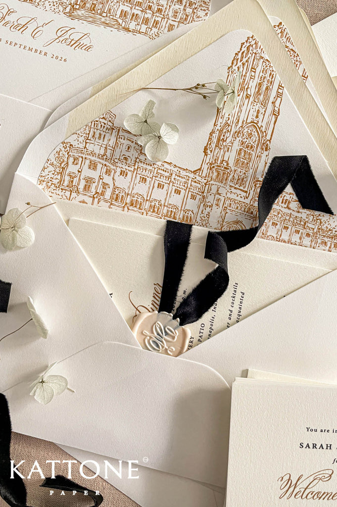 Wedding envelopes arranged in flat lay showcasing custom venue liners with detailed architectural artwork.