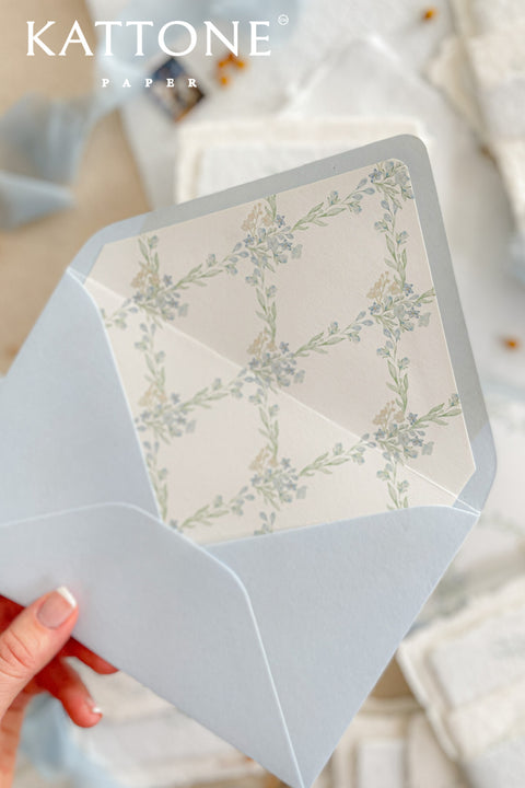Close-up of watercolor floral envelope liner inside light blue envelope showing delicate botanical artwork and smooth premium paper texture.