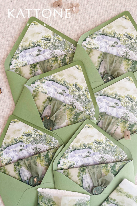 Pear green wedding envelopes with watercolor venue envelope liners styled on neutral linen with wax seals and fine art stationery details.