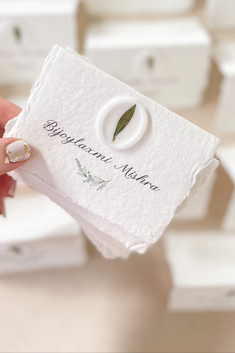 Add an organic, fine-art touch to your event with our handmade paper place cards, crafted from luxurious cotton rag paper with naturally torn deckled edges. Each card features a white botanical wax seal embedded with a real leaf, paired with elegant calligraphy for a soft, romantic aesthetic. Perfect for weddings, garden celebrations, and refined gatherings, these artisan-crafted place cards bring natural beauty and timeless charm to any tablescape.