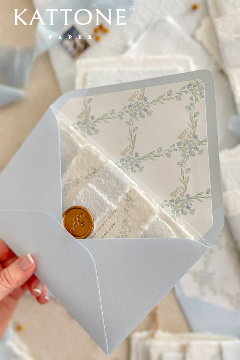 Stack of light blue envelopes with floral liners visible, highlighting consistent color, refined paper quality, and elegant stationery finish.