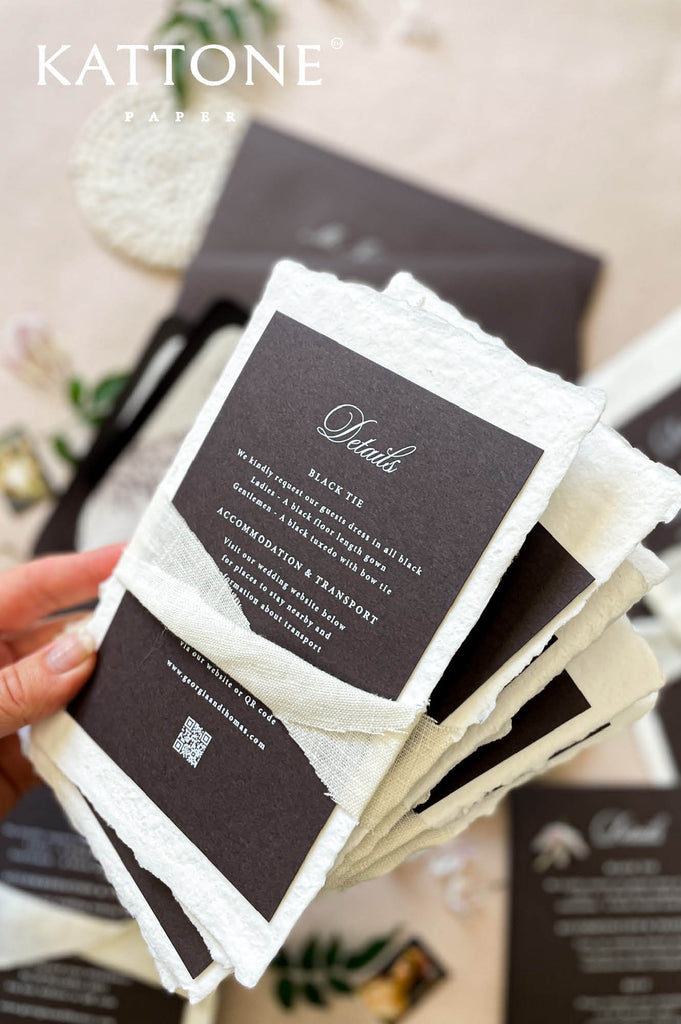 Fine art handmade paper wedding invitation suite with dark envelopes, silk ribbon, illustrated liners, editorial styling.