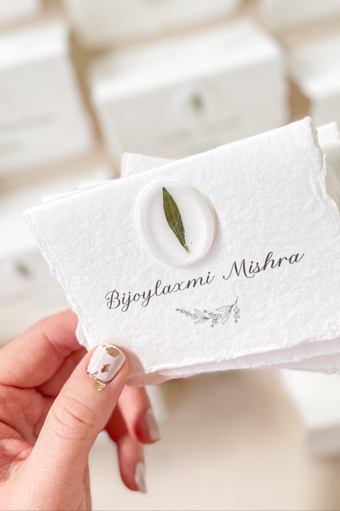 Add an organic, fine-art touch to your event with our handmade paper place cards, crafted from luxurious cotton rag paper with naturally torn deckled edges. Each card features a white botanical wax seal embedded with a real leaf, paired with elegant calligraphy for a soft, romantic aesthetic. Perfect for weddings, garden celebrations, and refined gatherings, these artisan-crafted place cards bring natural beauty and timeless charm to any tablescape.