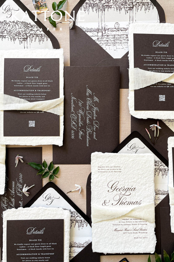 Stacked handmade paper wedding invitations with deckled edges and charcoal envelopes, modern luxury wedding stationery.