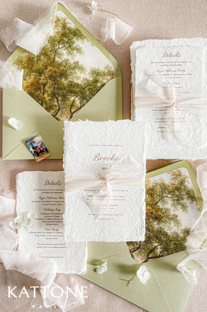 Luxury handmade paper wedding invitation suite featuring deckled edge cotton paper, ivory chiffon ribbon, sage green envelopes, custom scenic envelope liners, and elegant fine art wedding stationery styling.