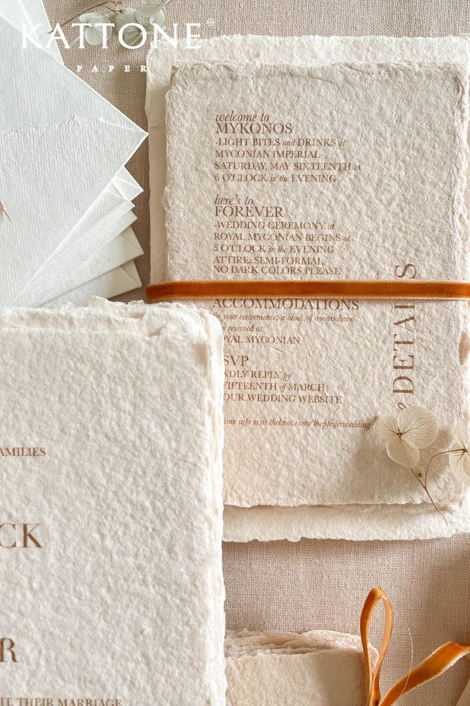 Close up of textured handmade cotton paper invitation highlighting organic deckled edges and modern serif typography in warm neutral tones.
