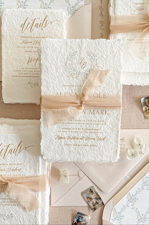 Luxury handmade paper wedding invitation suite featuring deckled edge cotton paper, blush chiffon ribbon, custom floral envelope liners, botanical monogram artwork, and romantic fine art wedding stationery styling.
