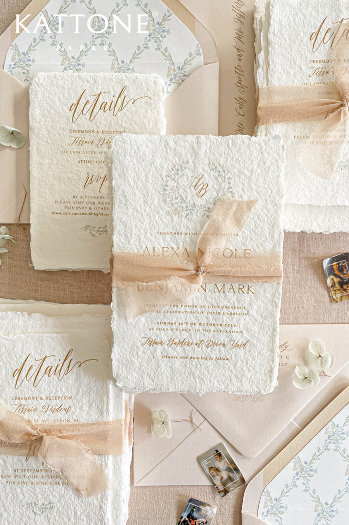 Luxury handmade paper wedding invitation suite featuring deckled edge cotton paper, blush chiffon ribbon, custom floral envelope liners, botanical monogram artwork, and romantic fine art wedding stationery styling.