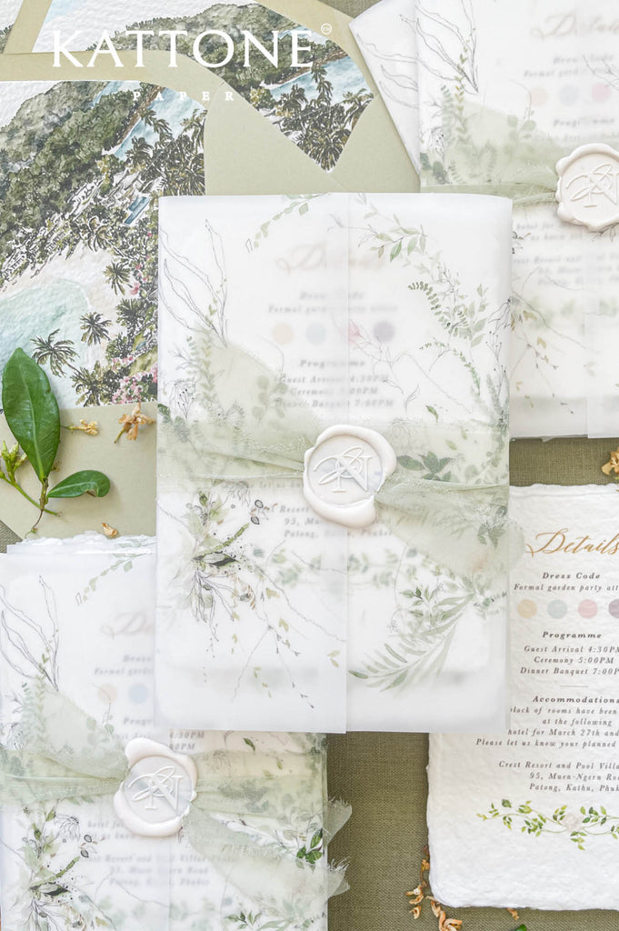 Wedding invitation wrapped in translucent vellum revealing botanical watercolor artwork on handmade paper.