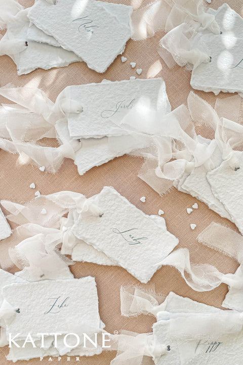 Assorted handmade paper wedding place cards with personalized guest names for elegant reception tables.