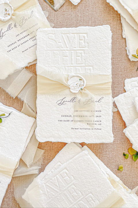 Announce your wedding with timeless sophistication through our embossed handmade paper Save the Date cards, featuring a subtle raised “Save the Date” design pressed into luxury cotton paper with deckled edges. Each piece is wrapped in a soft cream silk ribbon and sealed with a custom wax seal, creating an heirloom-quality keepsake that radiates romance and fine-art elegance.