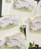 Custom watercolor venue envelope liner featuring a hand-painted Mediterranean villa, ivory textured envelope, soft neutral palette, luxury wedding stationery flat lay.