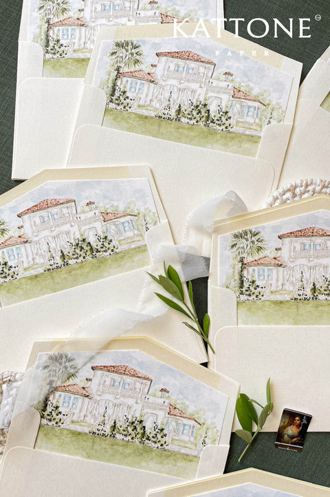 Custom watercolor venue envelope liner featuring a hand-painted Mediterranean villa, ivory textured envelope, soft neutral palette, luxury wedding stationery flat lay.
