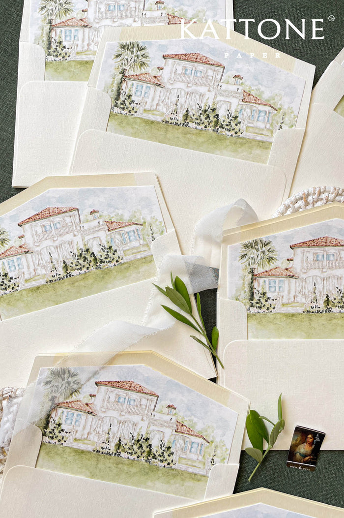 Custom watercolor venue envelope liner featuring a hand-painted Mediterranean villa, ivory textured envelope, soft neutral palette, luxury wedding stationery flat lay.