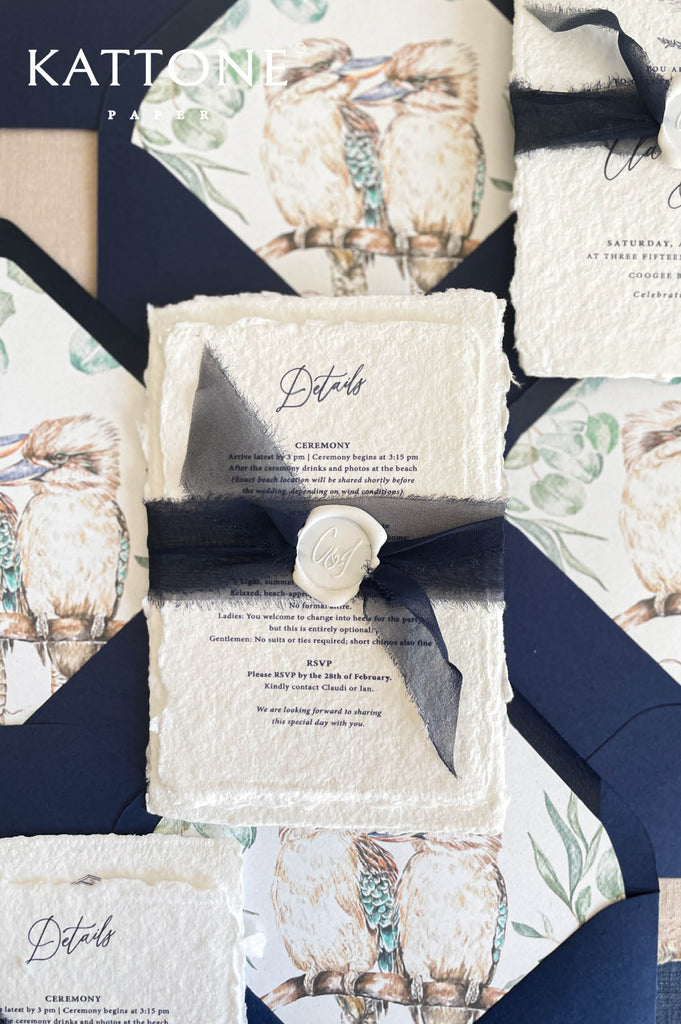Fine art wedding invitation suite styled in a flat lay with handmade paper invitations, inserts, envelopes and ribbon accents.
