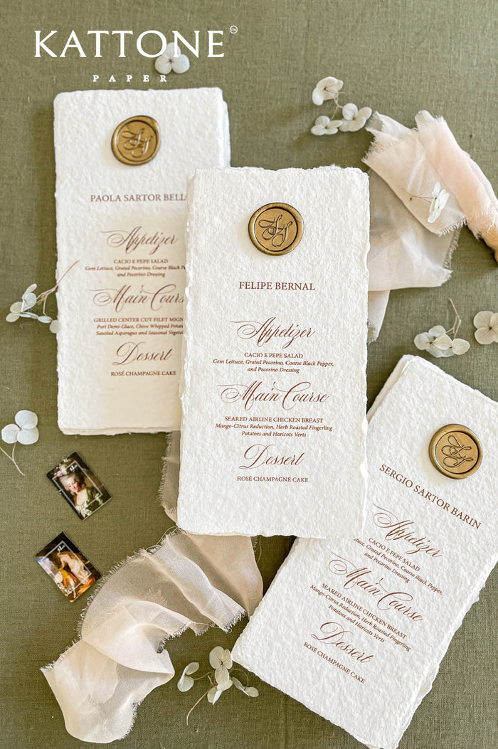 Handmade cotton paper wedding menus with deckled edges and elegant calligraphy typography, styled with wax seal accents and soft chiffon fabric.