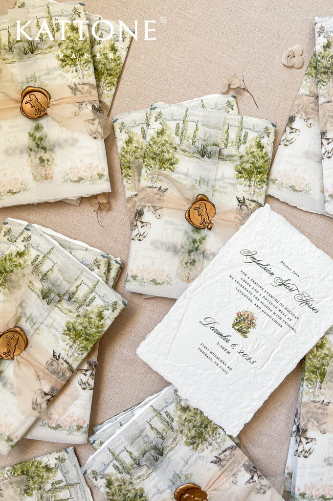 Fine-art wedding stationery styling with embossed handmade paper invitations, vellum wraps, and custom watercolor designs.