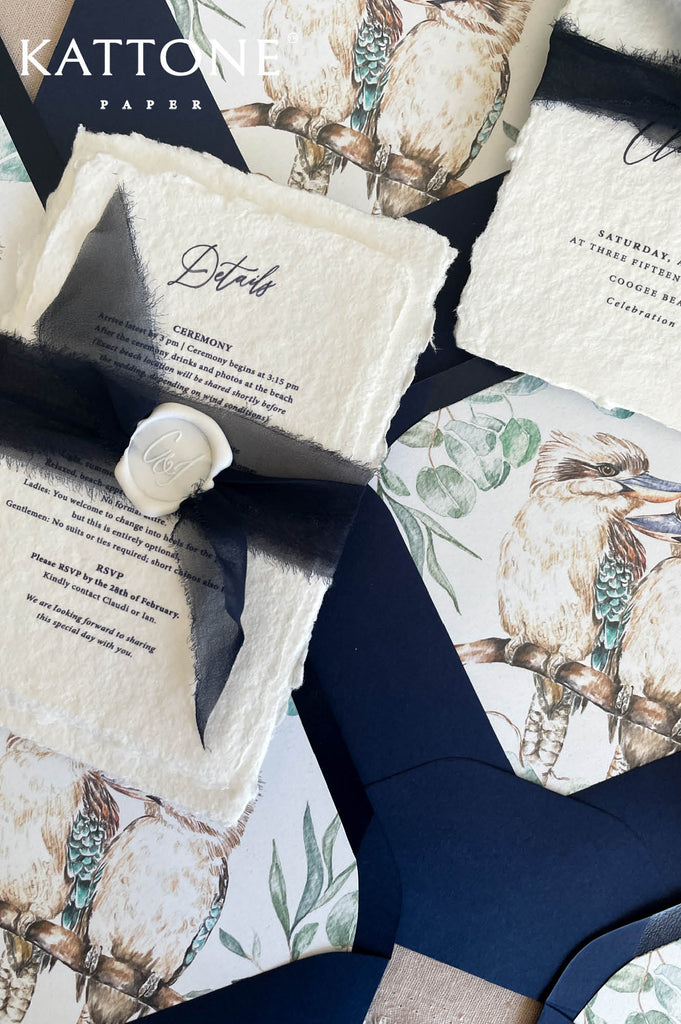 Close up of handmade cotton paper invitation highlighting textured deckled edges, architectural sketch and elegant typography.