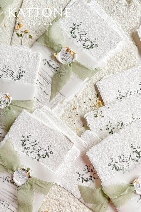 These handmade paper wedding menus are the epitome of timeless elegance and refined craftsmanship. Made from 100% cotton rag paper, each piece features a beautifully textured surface and natural deckled edges, exuding the charm of fine art stationery. The menu design showcases a botanical-inspired monogram delicately printed in deep green ink, creating a harmonious blend of organic beauty and understated luxury.