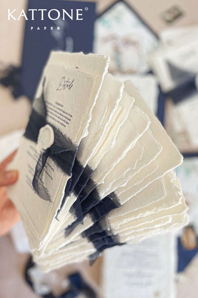 Handmade cotton paper with visible fibers and organically torn deckled edges creating a soft artisanal texture.