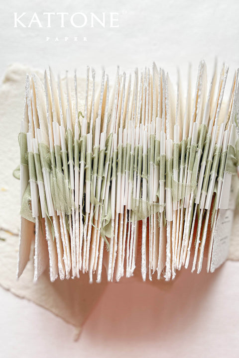 These handmade paper wedding menus are the epitome of timeless elegance and refined craftsmanship. Made from 100% cotton rag paper, each piece features a beautifully textured surface and natural deckled edges, exuding the charm of fine art stationery. The menu design showcases a botanical-inspired monogram delicately printed in deep green ink, creating a harmonious blend of organic beauty and understated luxury.