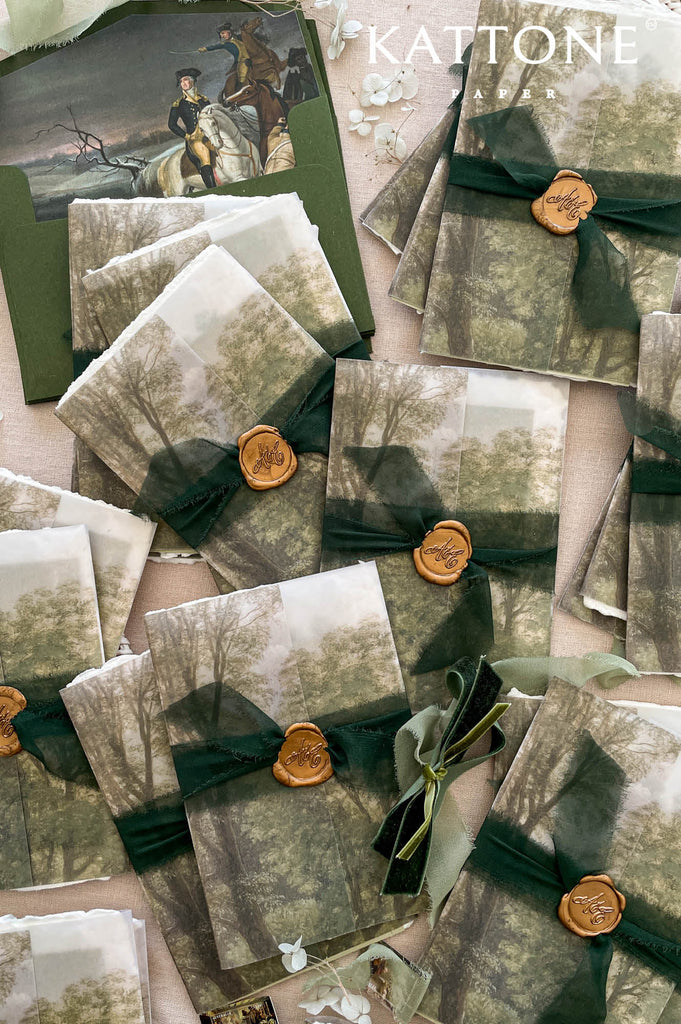 Soft translucent vellum covers wrapped around invitation inserts, subtly revealing romantic landscape artwork underneath for a layered and sophisticated presentation.