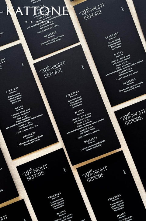 Flat lay of modern black wedding menus arranged for an elegant rehearsal dinner tablescape.