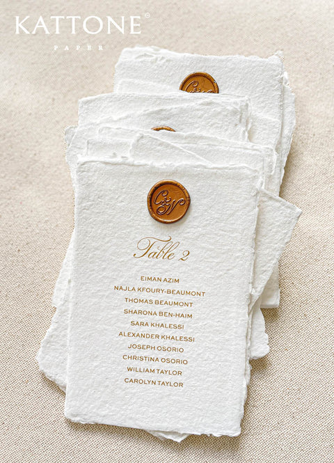Crafted from luxurious handmade cotton paper, these table numbers combine elegant gold typography with a signature wax seal for a truly elevated seating display. The natural deckle edges and organic texture add fine-art character, while the structured guest list layout ensures clarity and sophistication. Perfect for classic, luxury, and romantic weddings, this design brings a bespoke, heirloom quality to every reception table.