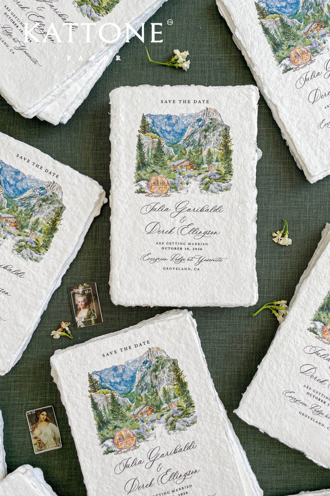 Flat lay of luxury save the date cards printed on handmade paper with custom watercolor venue illustration.