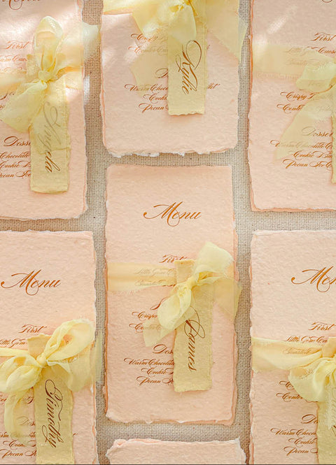 Bring warmth and romantic elegance to your tables with our colored handmade paper menus, crafted on premium cotton paper with softly deckled edges. Each piece features beautiful script typography, custom name tags, and silk-chiffon ribbons that add delicate texture and charm. Perfect for spring, garden, or fine-art weddings, these menus blend artisanal craftsmanship with graceful color palettes to complete your reception styling.