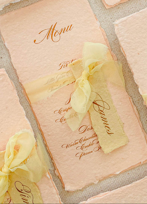 Bring warmth and romantic elegance to your tables with our colored handmade paper menus, crafted on premium cotton paper with softly deckled edges. Each piece features beautiful script typography, custom name tags, and silk-chiffon ribbons that add delicate texture and charm. Perfect for spring, garden, or fine-art weddings, these menus blend artisanal craftsmanship with graceful color palettes to complete your reception styling.