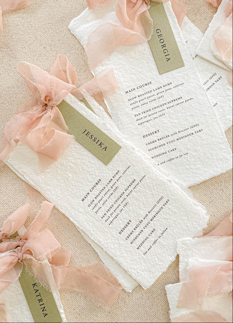 Add elegance and personalization to your tables with our handmade paper menus with name tags, crafted from luxury cotton paper with naturally deckled edges. Each menu features a custom guest name tag tied with a soft blush chiffon ribbon, blending artistry and function. Perfect for romantic, garden, or fine-art weddings, these menus double as place cards - creating a cohesive, bespoke dining experience.