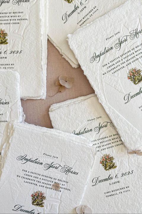 Close-up of embossed handmade paper wedding invitation showing watercolor artwork, textured cotton paper, and fine embossing.