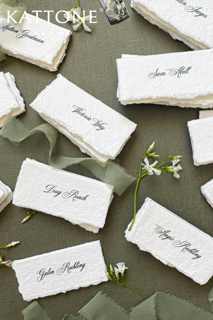 Assorted handmade wedding place cards stacked and styled for a reception table.