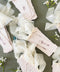 Blush handmade paper place cards with deckled edges, calligraphy names, and soft ribbon styling.