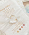 A close-up of a wedding invitation suite featuring a textured white envelope with gold foil script reading 'Wedding Weekend,' a white wax seal stamped with gold initials, and matching invitation cards in the background.